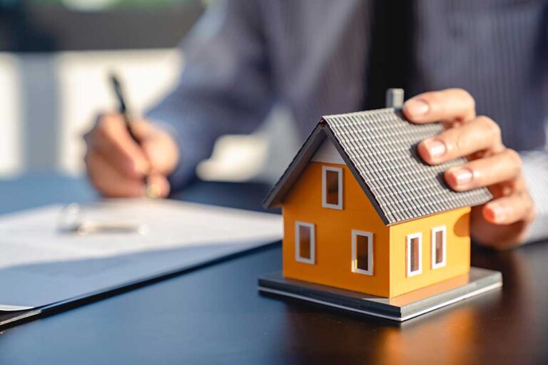 A family reviews paperwork while sitting at their kitchen table with a laptop and a stack of home documents.
